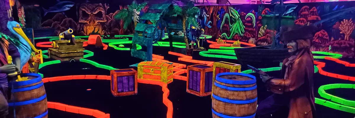 a pirate-themed indoor mini-golf course under black lighting